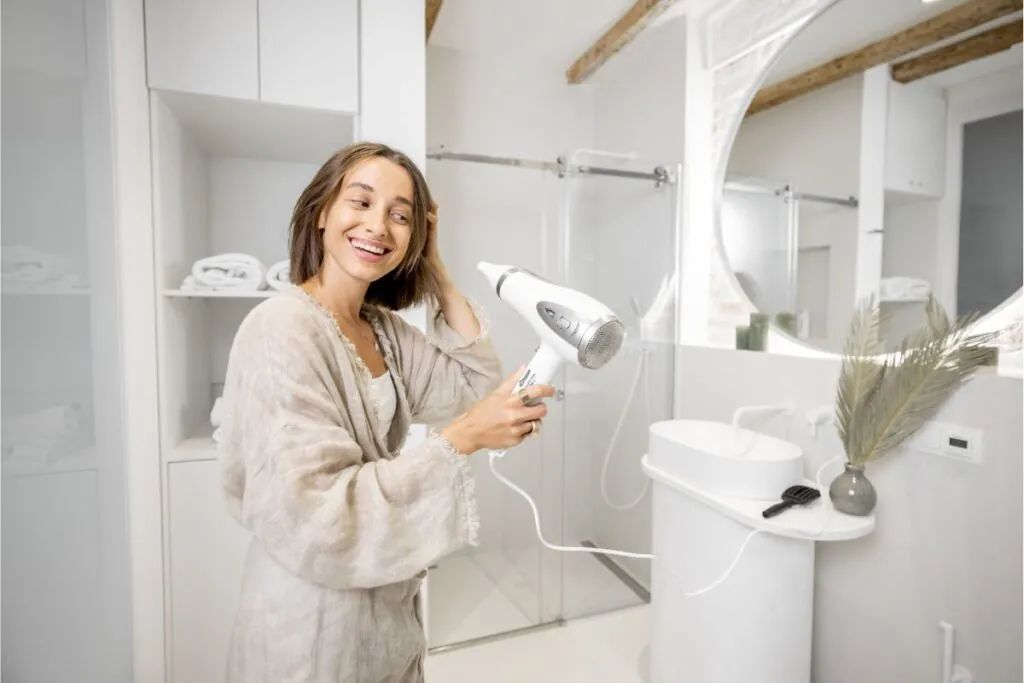 happy woman using hairdryer in the bathroom